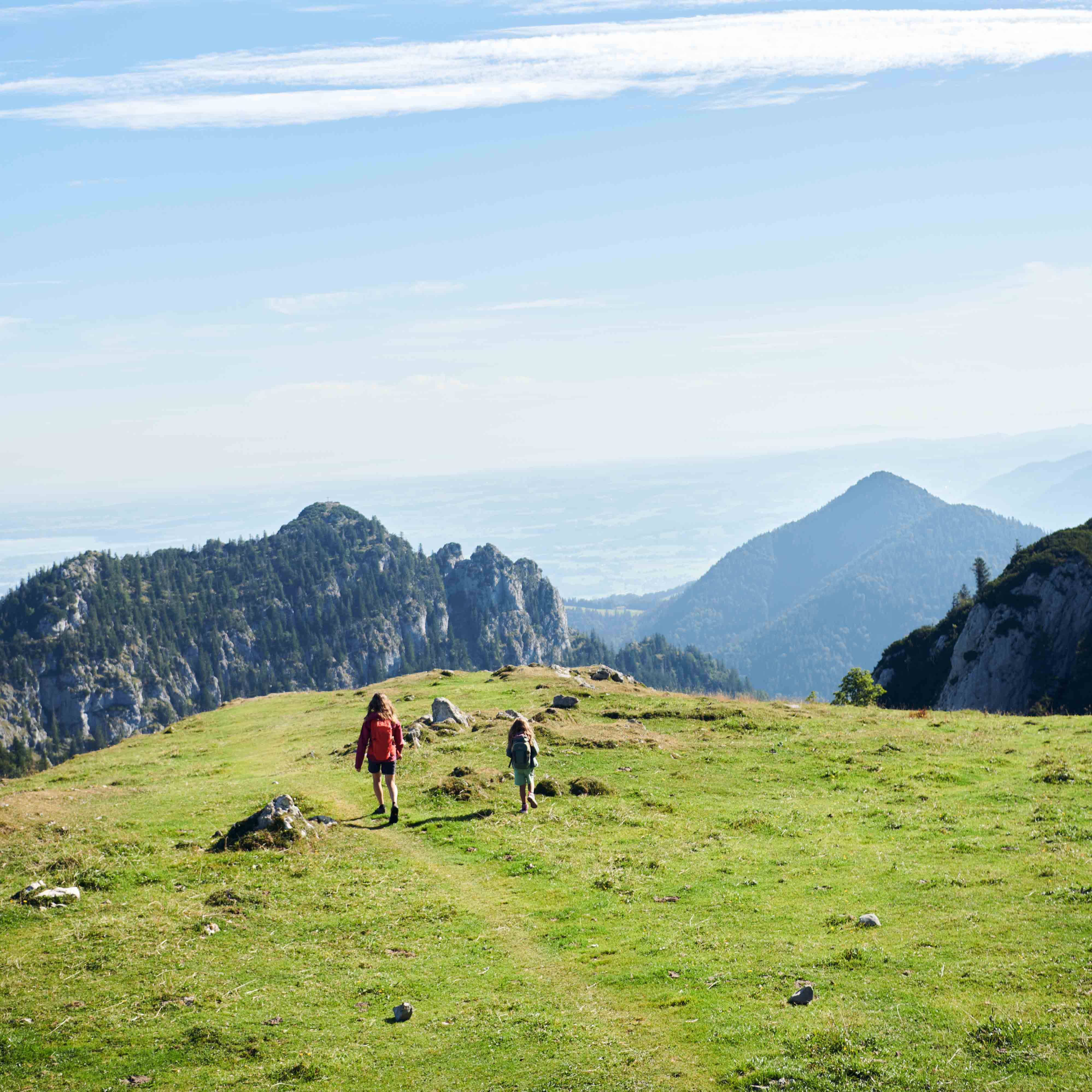 a woman and child walking on a grassy hill